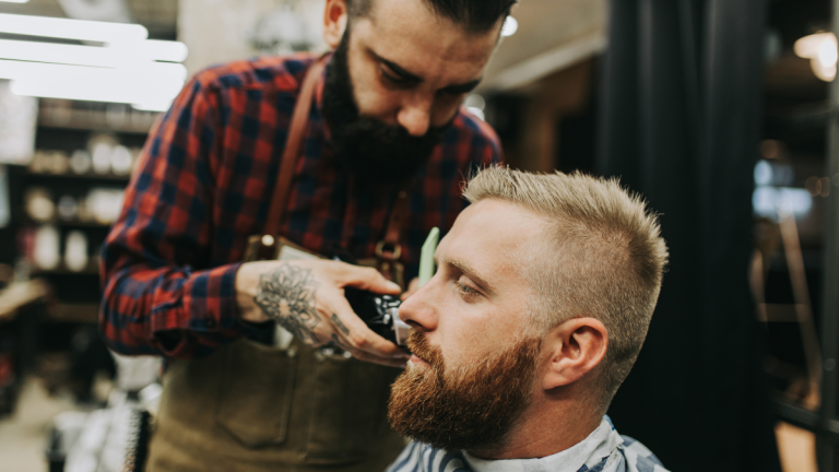 Barber trimming the beard of client sitting in his chair