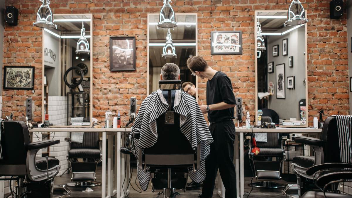 A barber talks to his client sitting in his barber chair about work life balance.