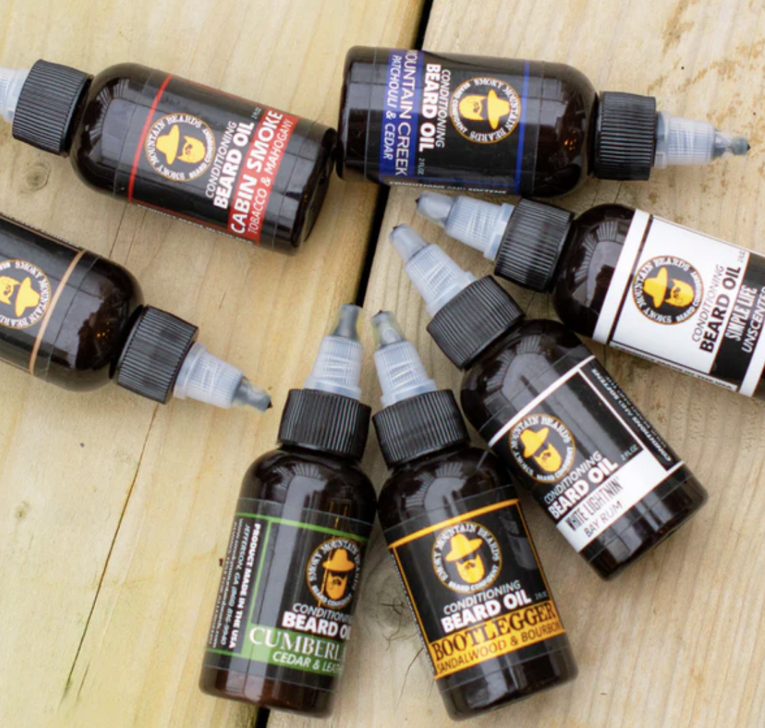 A group of beard oils are shown here on a wooden table.