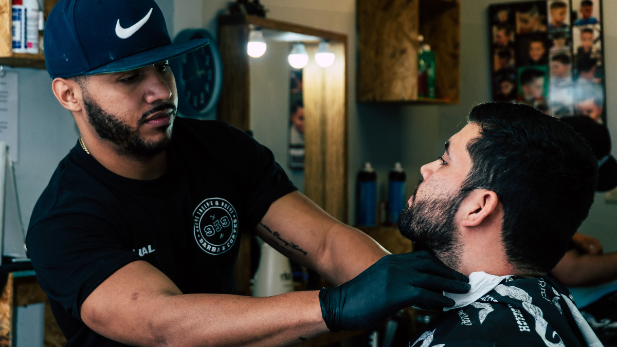 A barber works on his clients beard as they discuss how he can partner with a cause as a barber.
