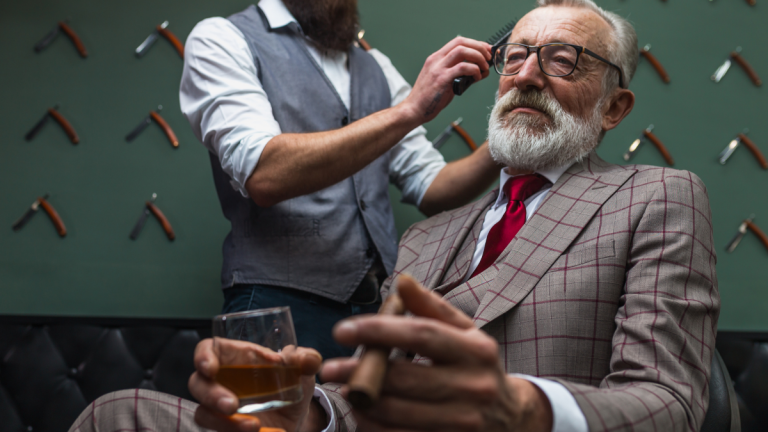 A barber cuts his clients hair while he sips on a drink at his barberbar.