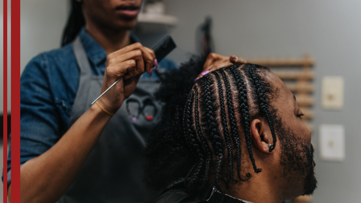 A client gets his hair braided in a barbershop that specializes in men's braiding